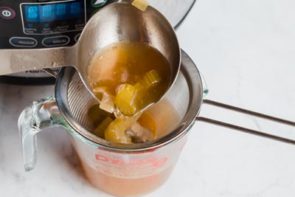straining out vegetables from chicken bone broth