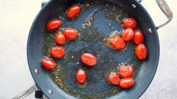 Cherry tomatoes cooking and bursting out juices.
