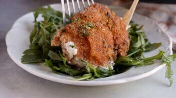 Plating a crispy piece of chicken on a bed of arugula lettuce.