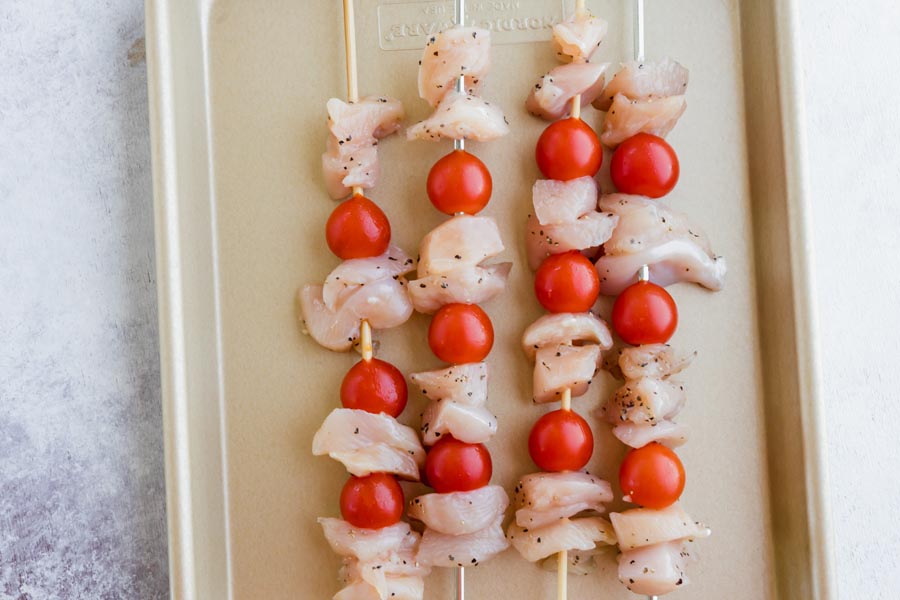 raw chicken threaded with tomatoes on skewers