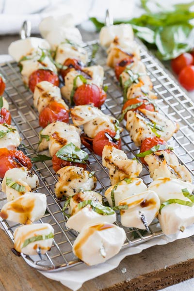 kebab on a cooling rack with tomato, chicken and cheese balls and topped with basil