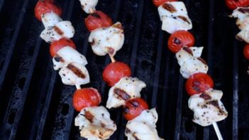 tomato and chicken kebabs cooking on a grill