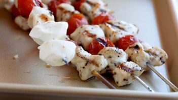 mozzarella cheese balls added to the end of a skewer filled with chicken and cherry tomatoes