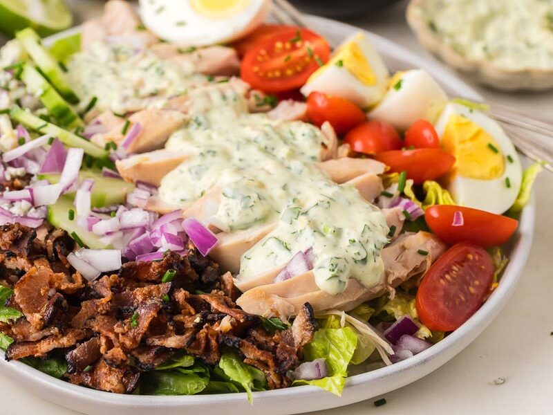Chicken Cobb salad with bacon, tomatoes, hard-boiled eggs and creamy avocado herb dressing.