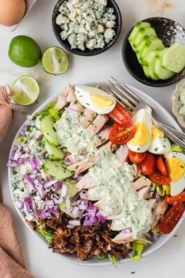 Single serving chicken cobb salad drizzled with creamy avocado herb dressing and served with fresh lime wedges.