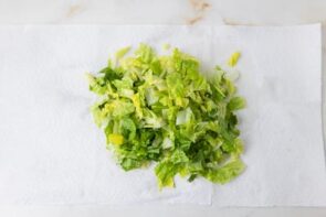 Chopped romaine lettuce spread on paper towels to dry before assembling a cobb salad.