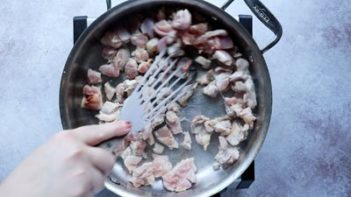 chicken cooking in a skillet and stirring it with a metal spatula