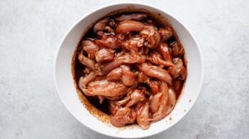 Raw chicken marinating in a bowl.