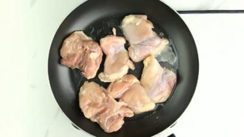 a nonstick skillet with raw chicken cooking