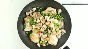 a skillet with cooked chicken and vegetables on top
