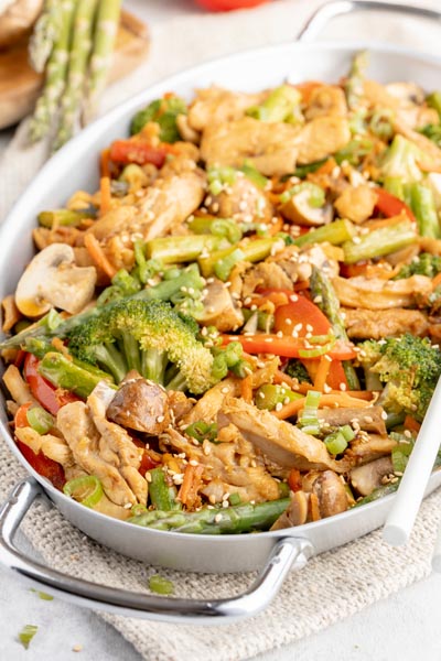 a metal pan loaded with colorful stir fry mix of broccoli, mushrooms and chicken
