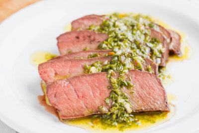 chopped herbs in oil cover slices of beef steak