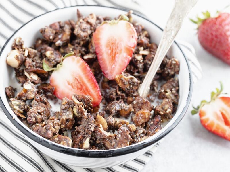 a spoon inside a bowl of cereal topped with strawberries