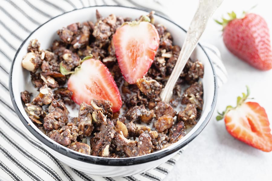 a spoon inside a bowl of cereal topped with strawberries