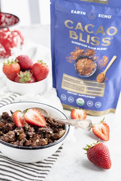 a bag of Cacao Bliss sits next to strawberries and a bowl of granola