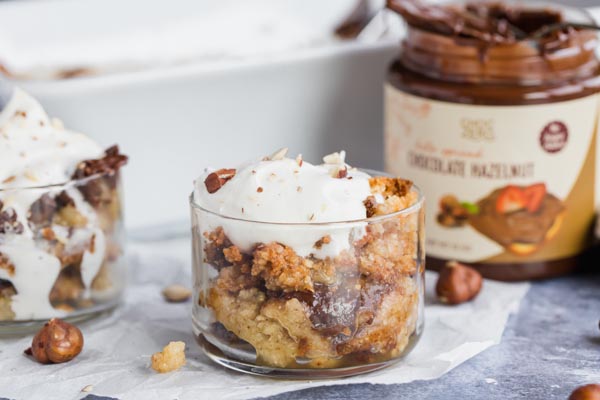 two containers with chocolate cake mix in it with hazelnuts around