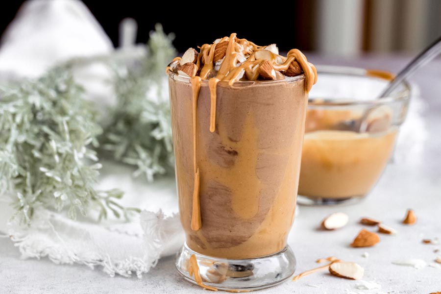 peanut butter chocolate smoothie with peanut butter on the sides and topped with nuts