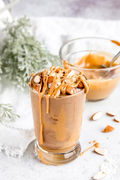 creamy chocolate smoothie topped with runny peanut butter and nuts