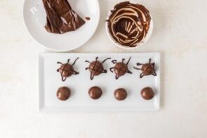 A tray showing chocolate protein balls in the process of being decorated with melted chocolate.