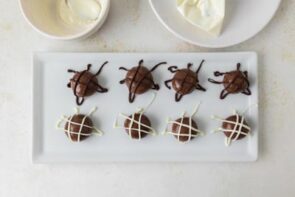 A tray of chocolate protein balls finished with white and dark chocolate drizzle designs.