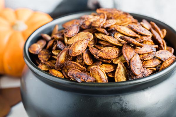 a black bowl full of seasoned roasted pumpkin seeds