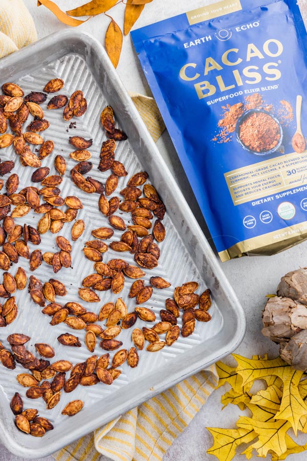 a tray of roasted pumpkin seeds next to a bag of chocolate cacao bliss