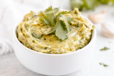 Thick and creamy cilantro aioli in a small white bowl topped with cilantro.