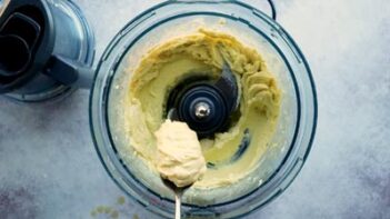 A spoonful of aioli over a food processor.