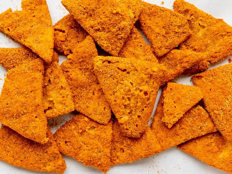 Crispy orange cottage cheese chips cut into triangles and coated in a bold, Dorito-style seasoning.
