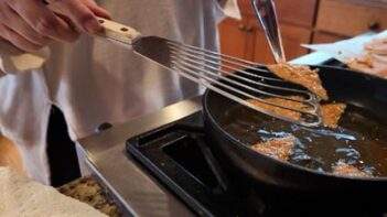 Cottage cheese chips frying in hot oil in a skillet to achieve extra crispiness.