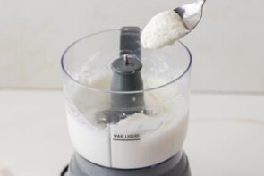 Cottage cheese being added to a food processor to create a smooth base for the pancake batter.