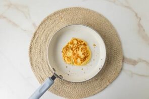 Single cottage cheese pancake cooking in a small skillet.