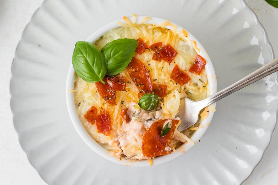 A fork digging into a cottage cheese pizza bowl topped with pepperoni.