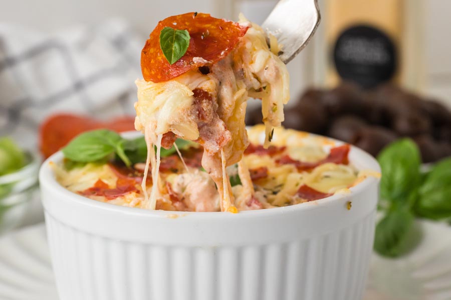A fork pulling out a bite of cottage cheese pizza bowl and showing the melted cheese.