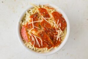 A cottage cheese bowl topped with sliced pepperoni and shredded parmesan cheese.
