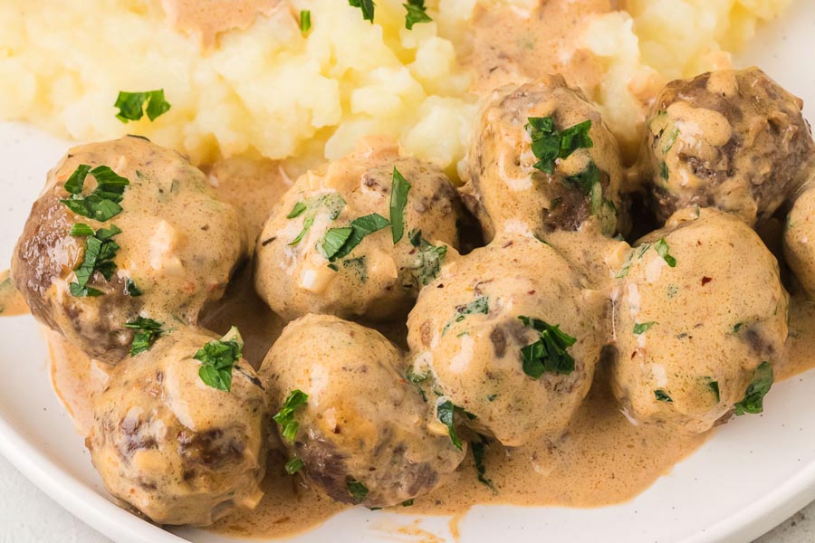 Creamy cowboy butter meatballs coated in a rich garlic butter sauce and garnished with fresh parsley, served alongside mashed cauliflower.