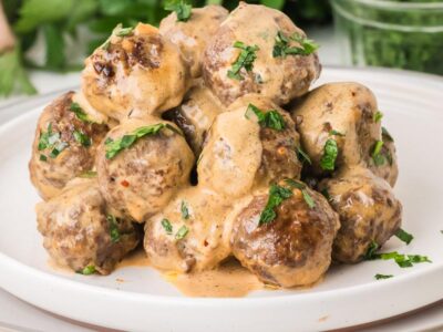 A stack of tender cowboy butter meatballs smothered in creamy garlic butter sauce and garnished with fresh parsley.