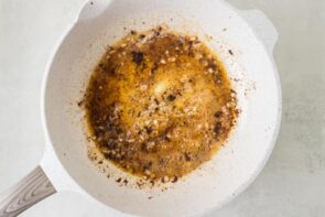 Melted butter, garlic, herbs, and seasonings simmering in a skillet to make cowboy butter sauce.