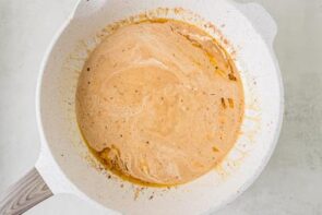Creamy cowboy butter sauce simmering in a skillet with garlic, herbs, and spices.