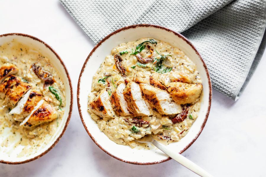 two white plates of creamy chicken with a gray napkin on the side