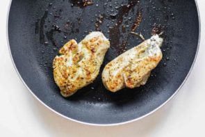two chicken breasts cooking in a non-stick skillet