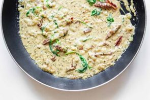 spinach and tomato in a cream sauce sitting in a skillet