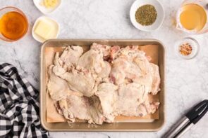 Coated chicken thighs on a baking tray.