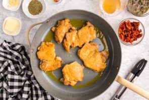 Golden pan seared chicken thighs in a skillet.