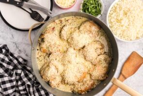 Grated parmesan on top of chicken thighs in a skillet.