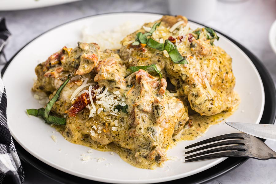 Creamy pesto chicken on a plate over cauliflower rice and topped with basil and shredded parmesan.