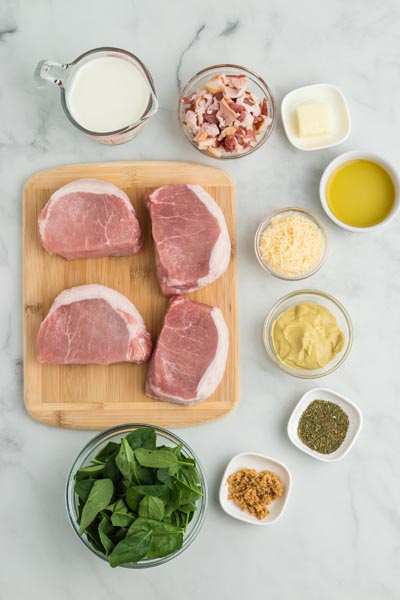 Ingredients for a pork chop recipe on a marbled counter.