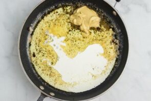 A skillet with melted butter, heavy cream and dijon mustard inside.