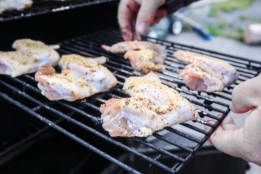 holding 5 chicken wings on a grill grate