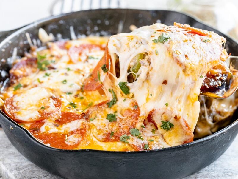 pulling out a cheesy slice of skillet pizza